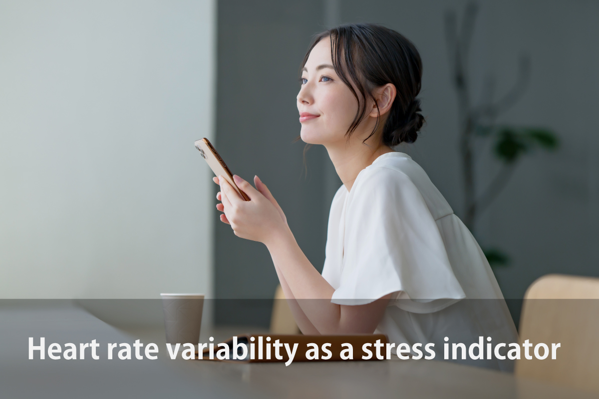 Heart rate variability as a stress indicator(スマホで心拍変動の数値を確認しながらストレスを軽減するカフェタイムの女性のイメージ画像)作成者:おかきソムリエ